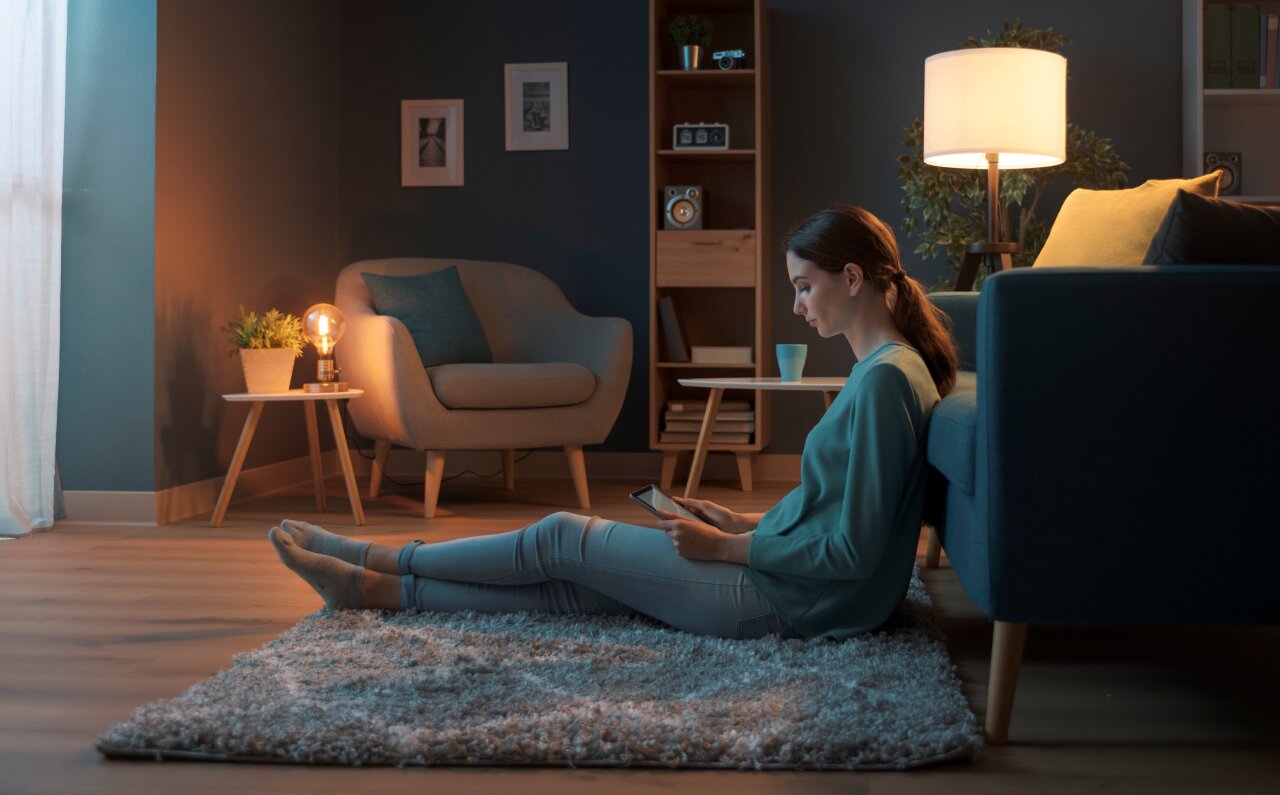 Frau sitzt im Wohnzimmer am Tablet