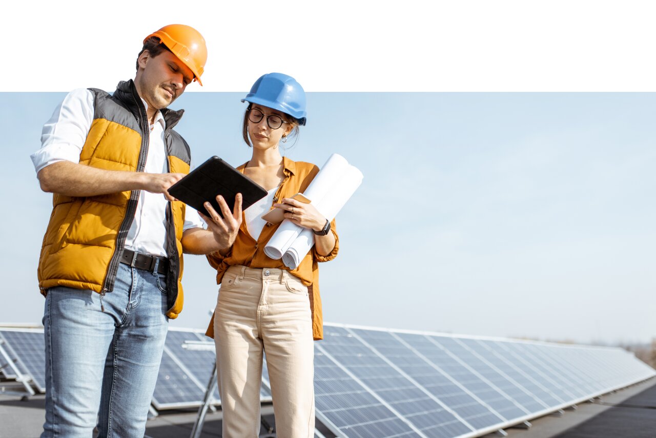 Mann und Frau bedienen ein Tablet. Im Hintergrund sind Photovoltaikplatten
